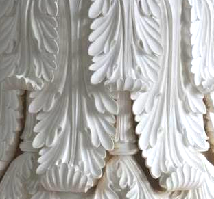 White mural detail of layered acanthus leaves, sculptural and ornate.