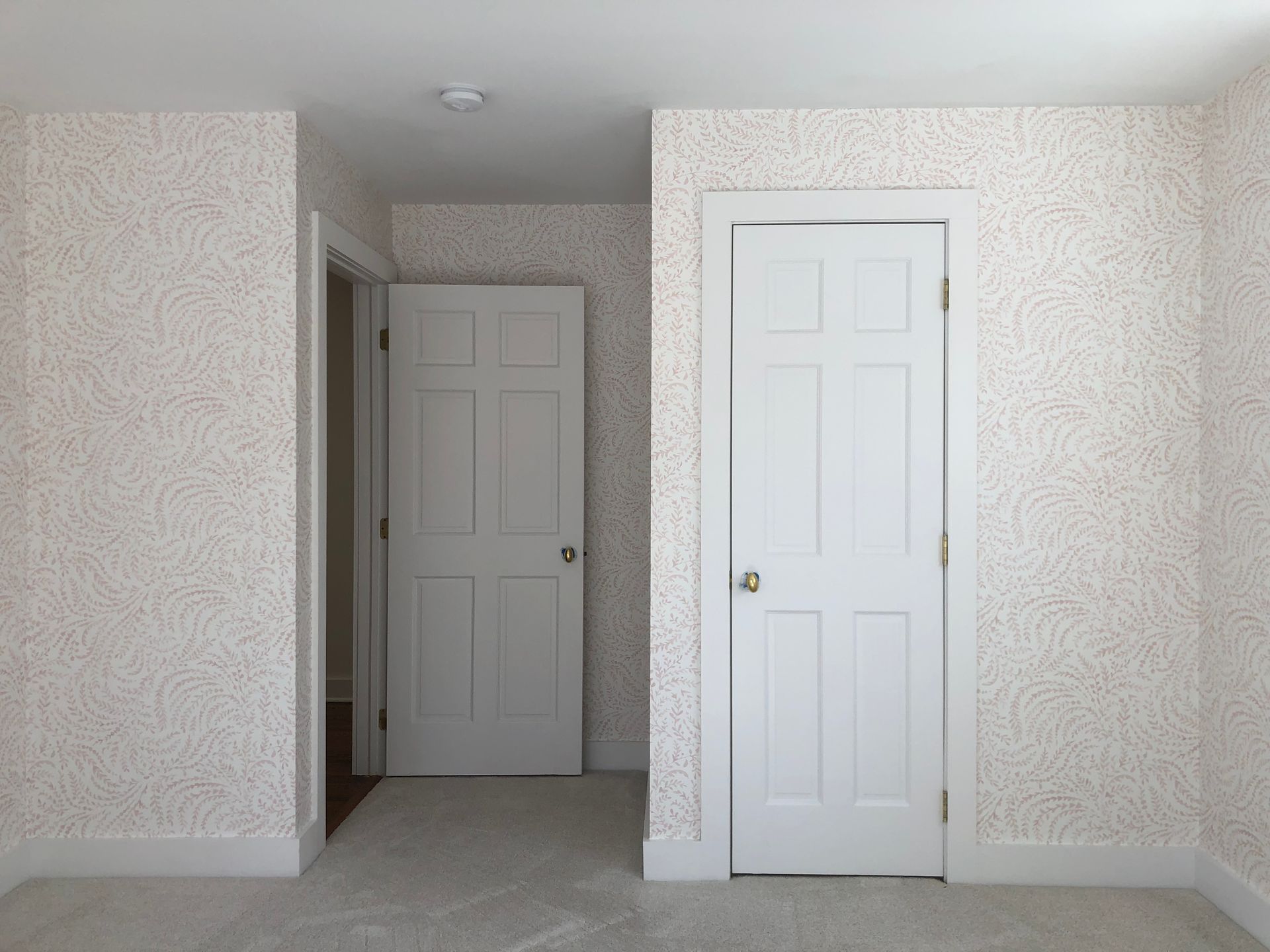 Hallway mural with three white doors and swirling wallpaper pattern.