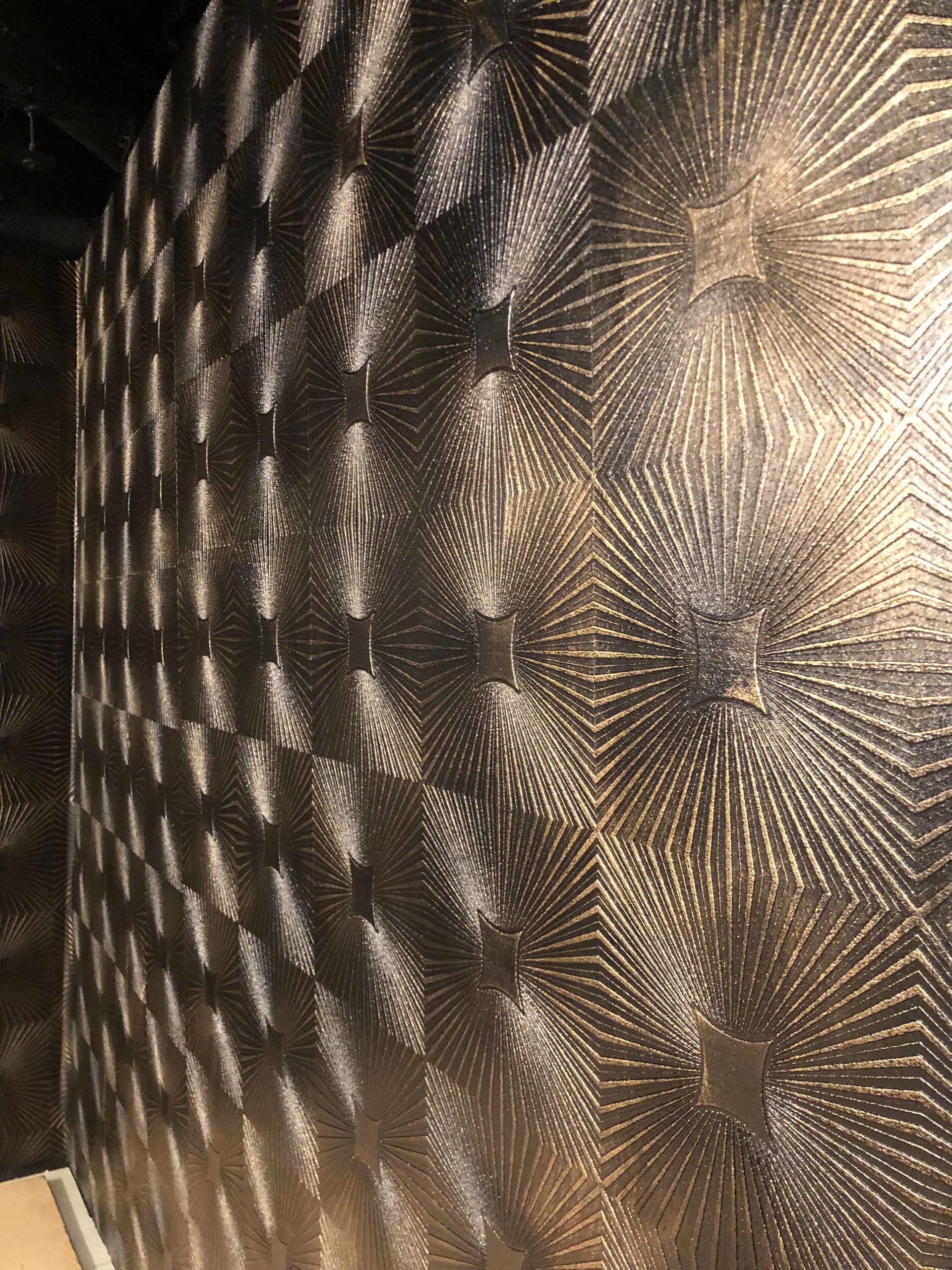 Geometric mural with diamond texture and metallic gold-brown sheen.