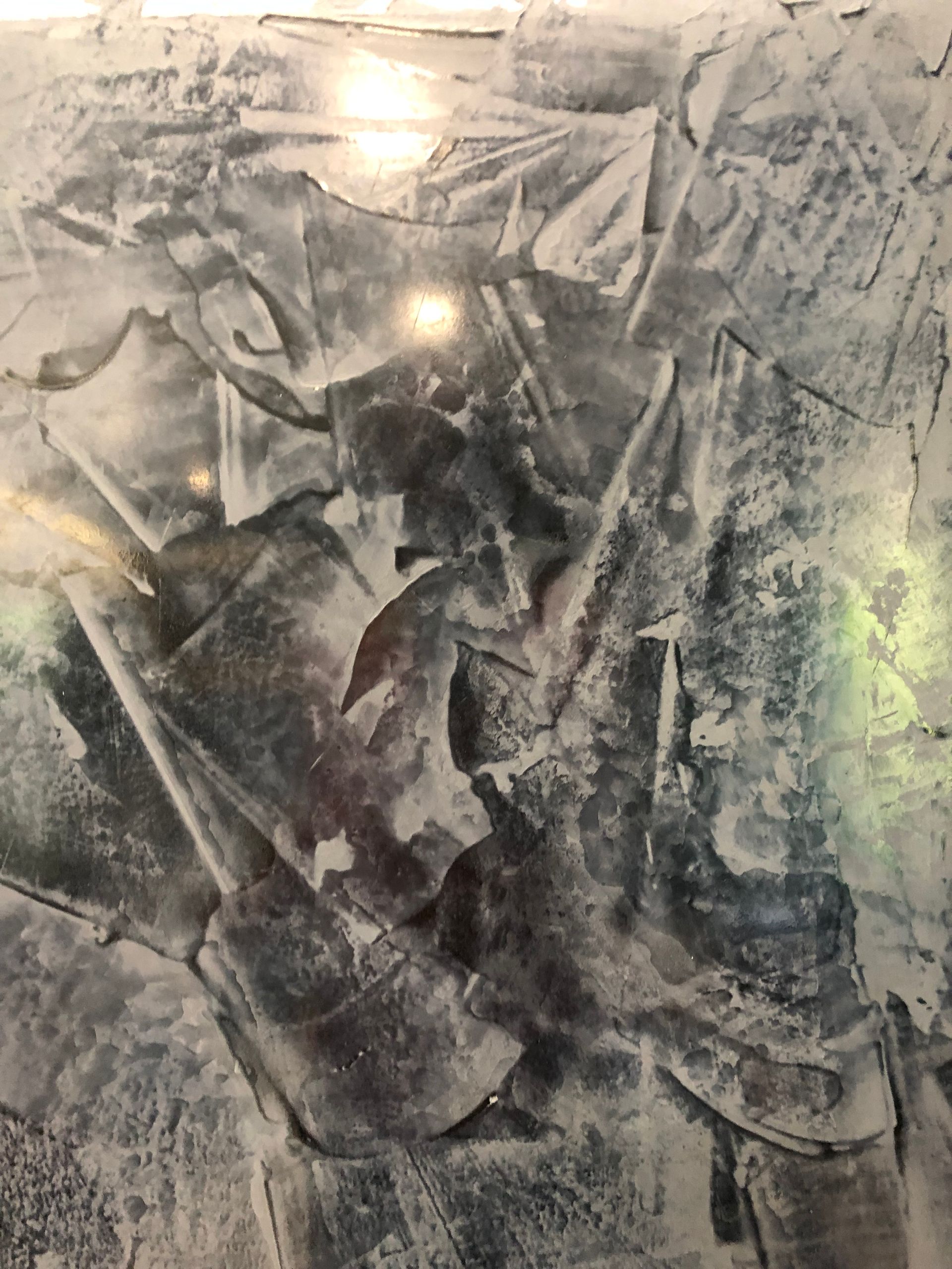 Textured surface with layered brush strokes in gray, white, and black, featuring glossy highlights and rugged finish.