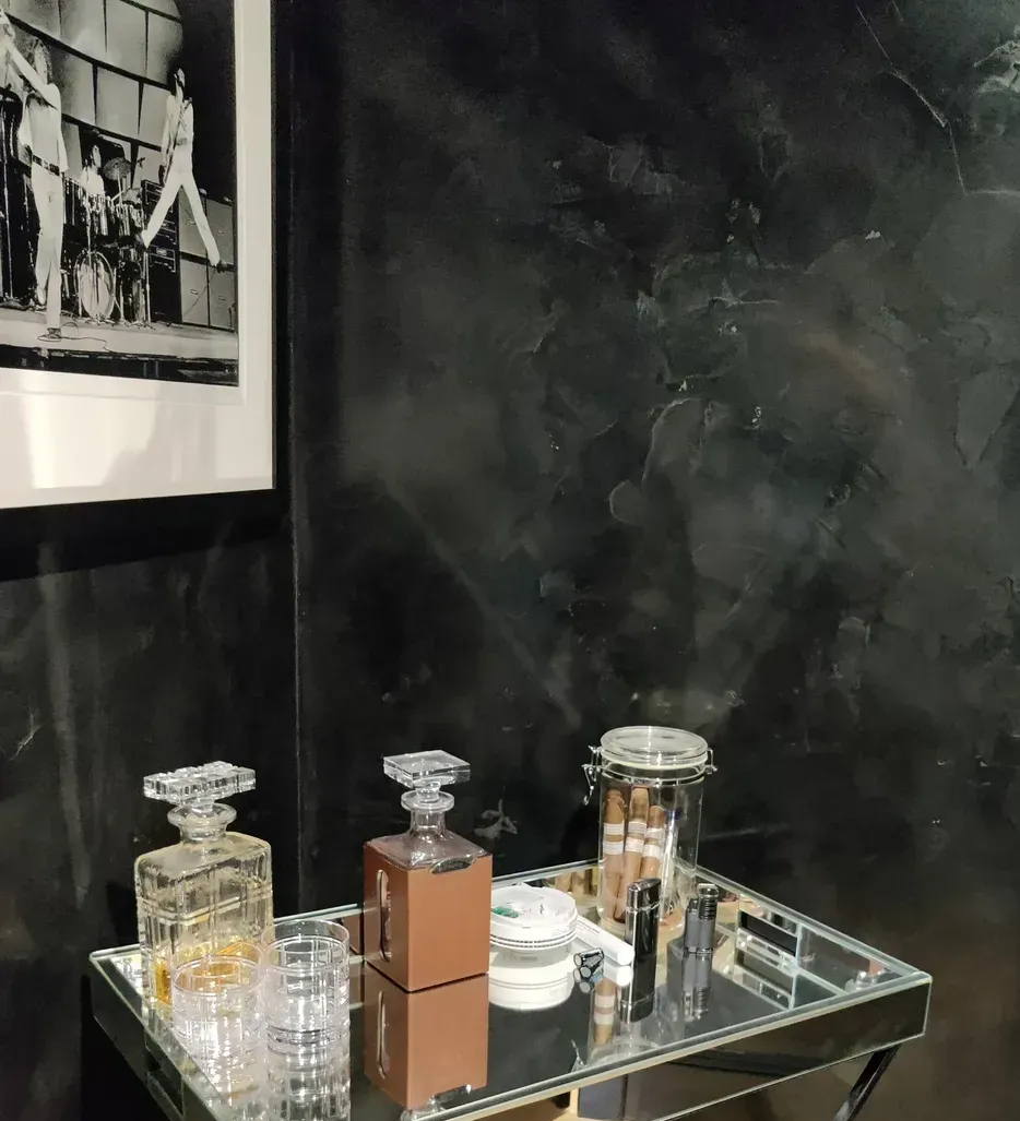 Elegant mirrored console with decanters, cigars, and accessories below a black-and-white photo of a mid-century musical performance.