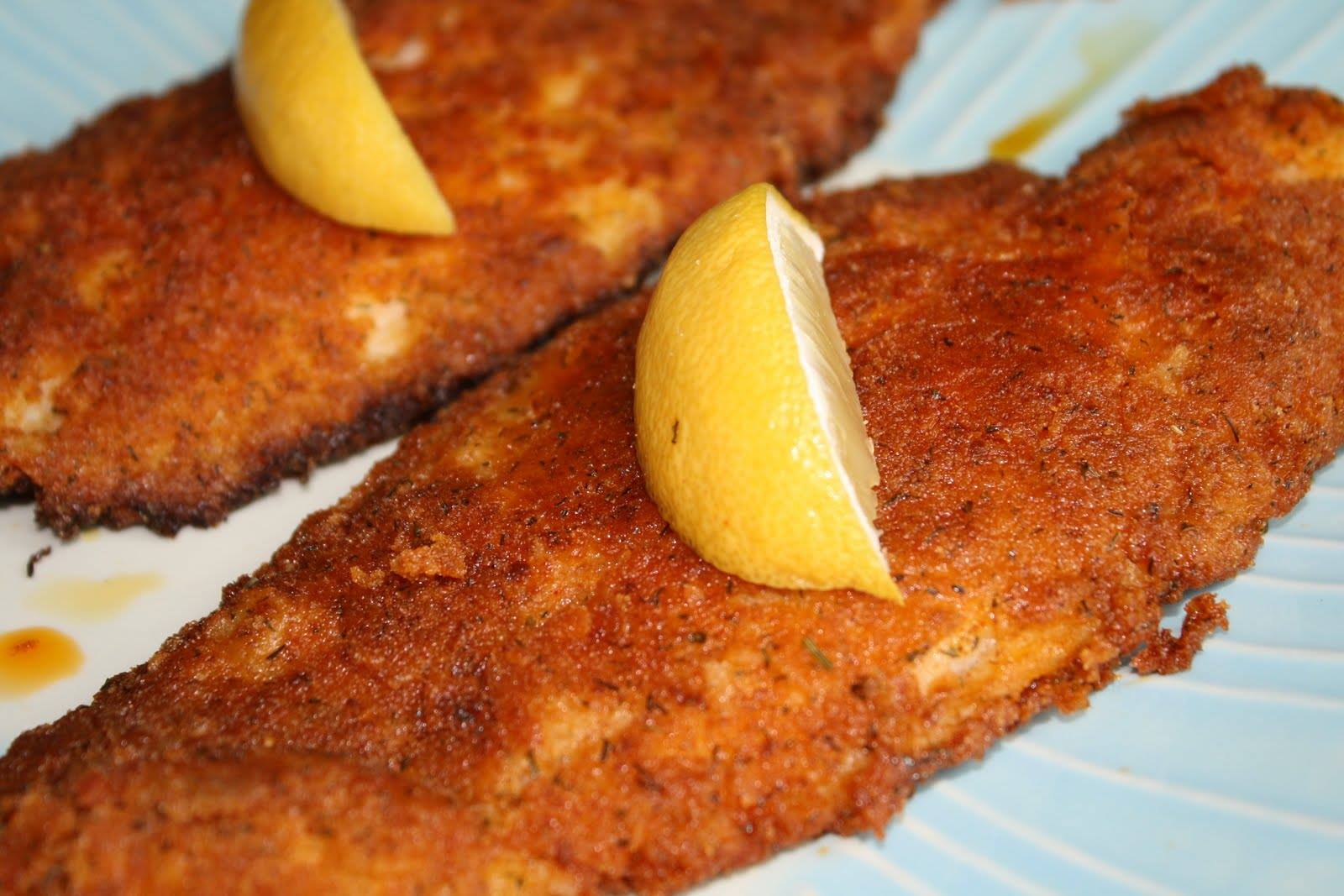 Two fried fish with lemon slices on a blue plate