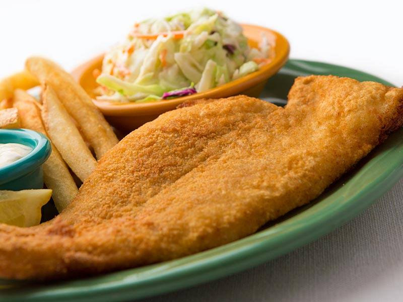 A green plate topped with fried fish , french fries and coleslaw.