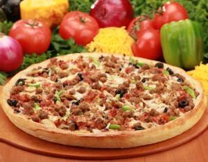 A pizza is sitting on a wooden cutting board surrounded by vegetables.