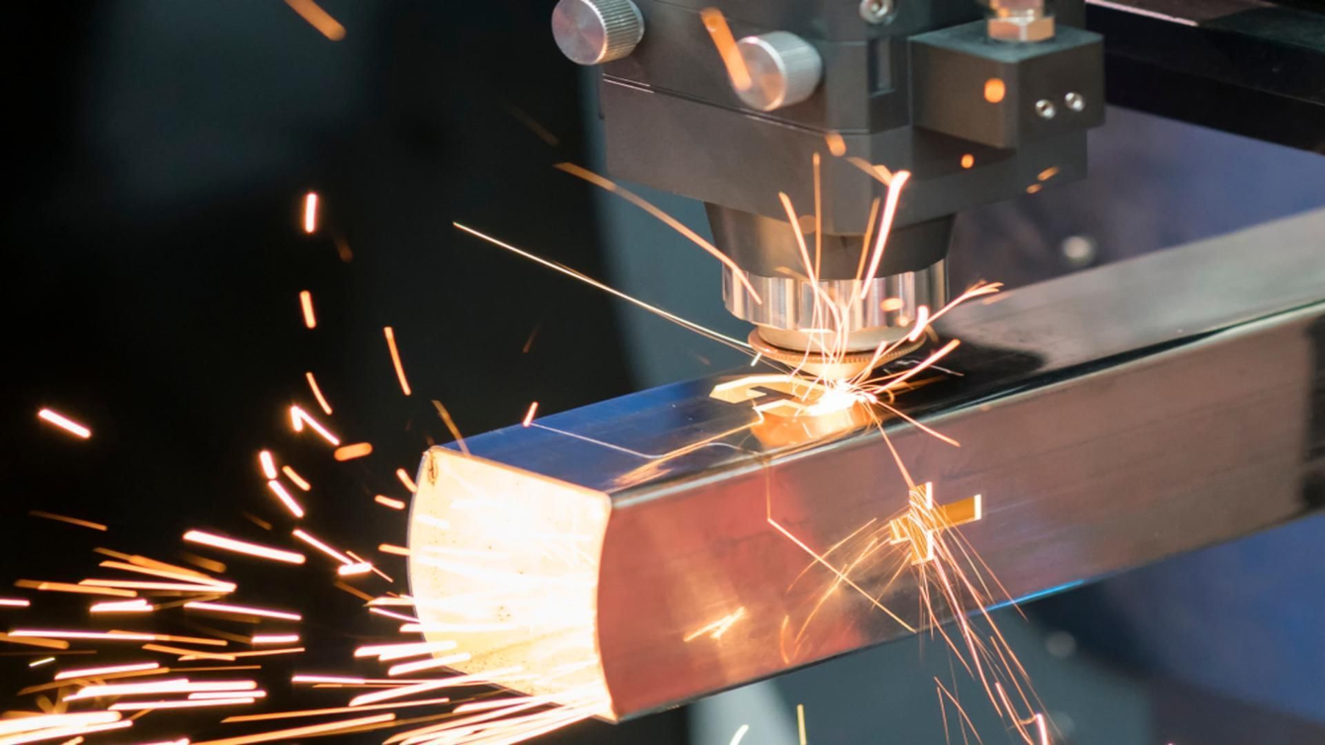 Laser Cutter Sparks as It Cuts A Metal Bar In A Factory — Sheetmetal Improvements & Design in Molendinar, QLD