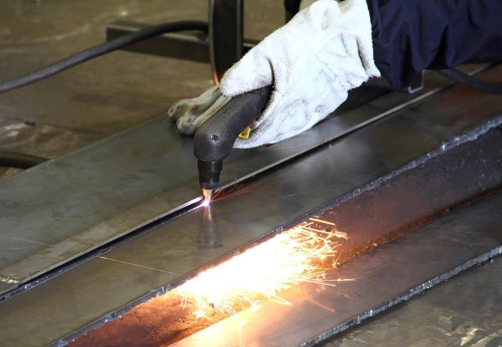 Person In Gloves Using A Plasma Cutter On Metal — Sheetmetal Improvements & Design in Tweed Heads, QLD