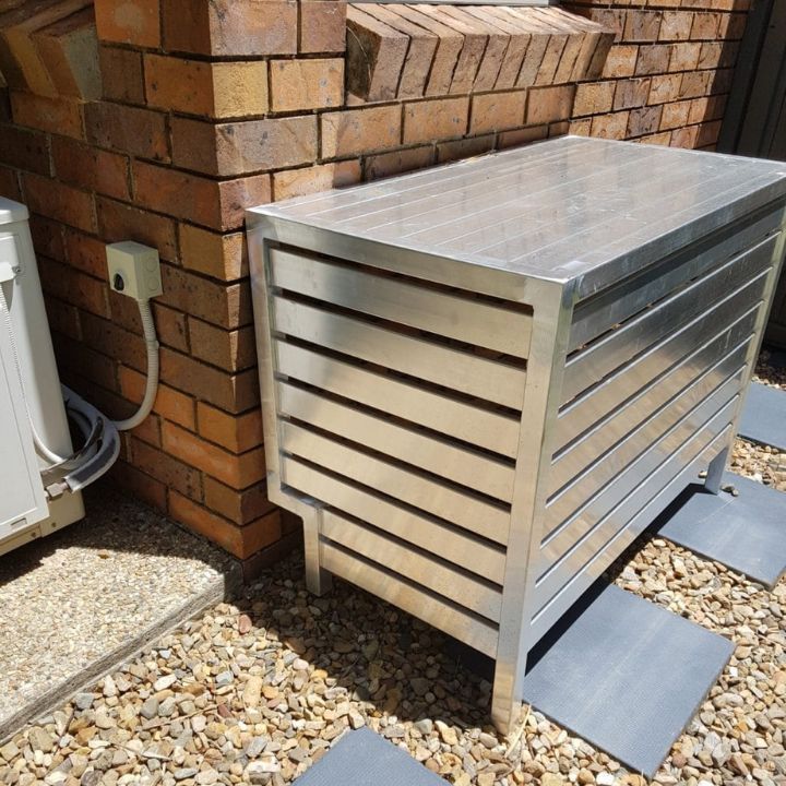 Metal Air Conditioner Cover Against Brick Wall On Gravel — Sheetmetal Improvements & Design in Burleigh Heads, QLD