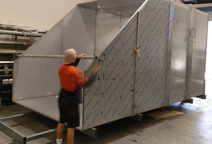 Man Working On A Large, Stainless Steel Industrial Structure Indoors — Sheetmetal Improvements & Design in Burleigh Heads, QLD