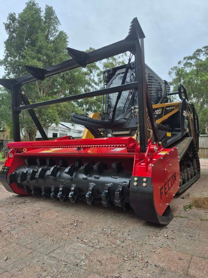 Red excavator demolishing concrete near a building with a worker inside— JC Excavation and Mechanical Pty Ltd in Raymond Terrace, NSW