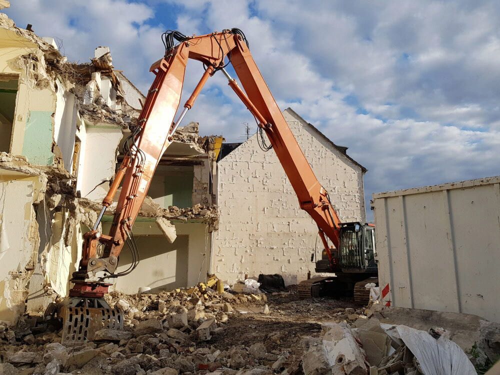 Orange Excavator Demolishing a Building With Rubble — JC Excavation and Mechanical Pty Ltd in Raymond Terrace, NSW