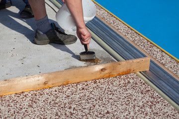 A person is painting a concrete surface with a brush.