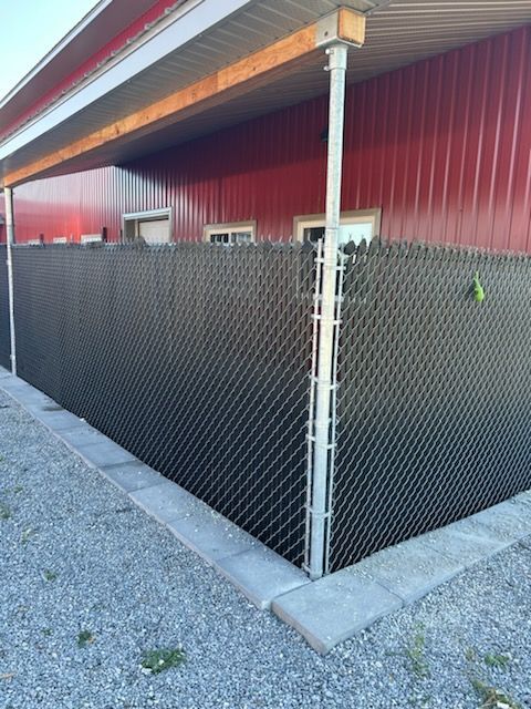 Clôture grillagée noire le long d'un bâtiment avec un extérieur rouge et un porche couvert.