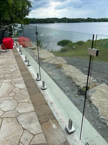 Garde-corps en verre le long d'un patio donnant sur un lac.