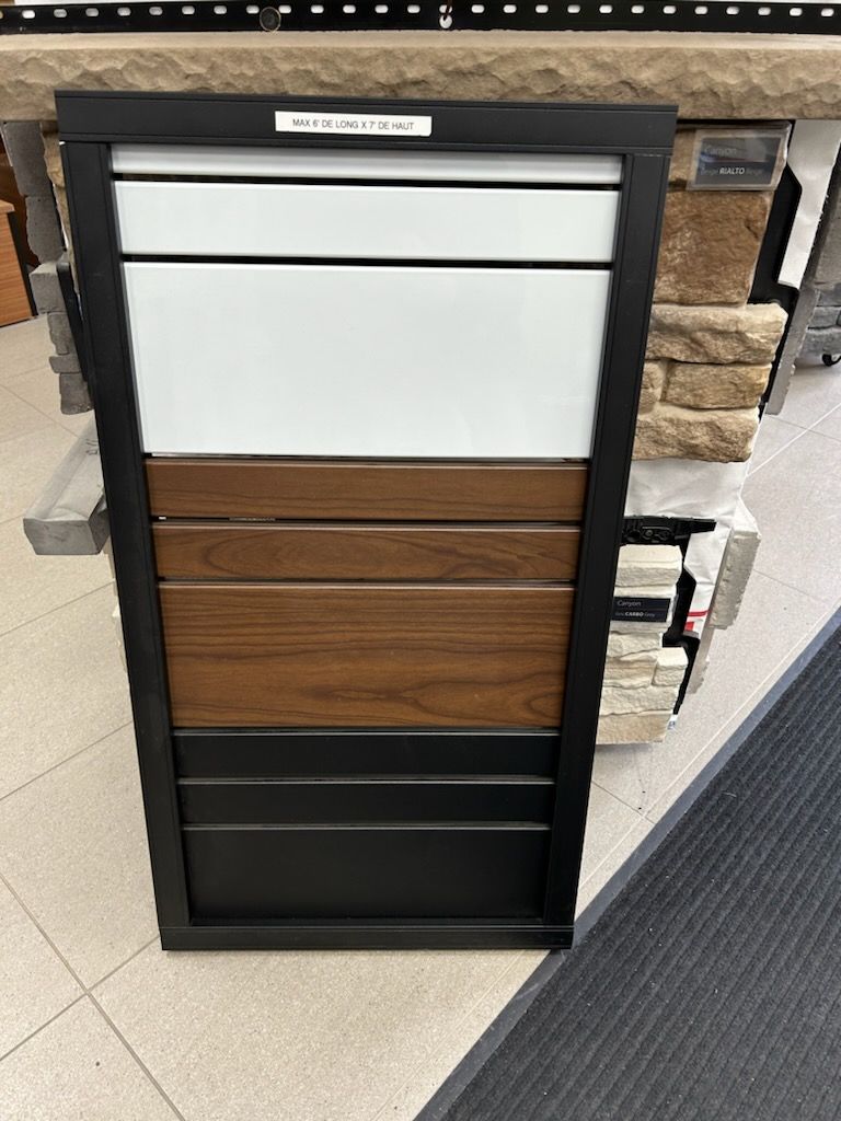 Tableau d'échantillons de couleurs avec panneaux blancs, tons bois et noirs dans un cadre noir.