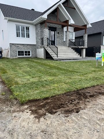 Une maison avec une façade en briques et une pelouse verte en construction.