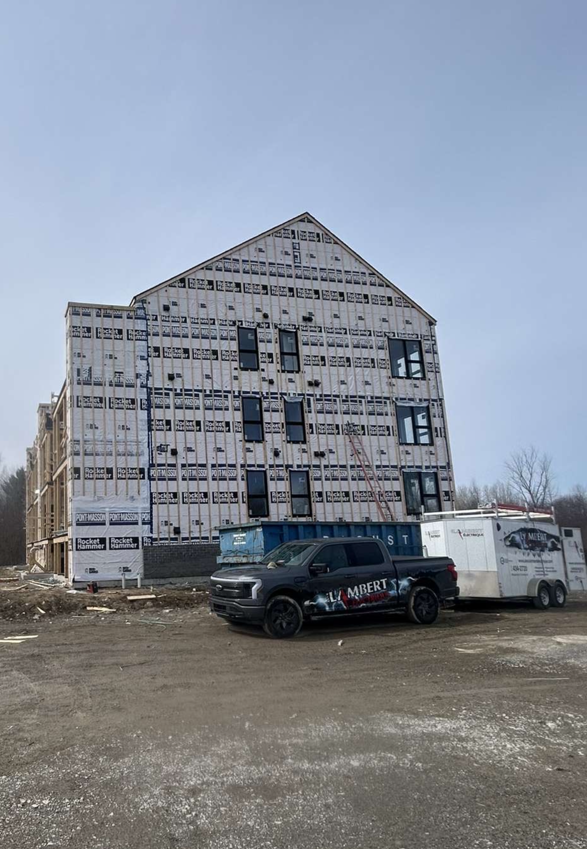 Cheminée avec des accents de bois, de la pierre blanche et une personne travaillant sur le mur.