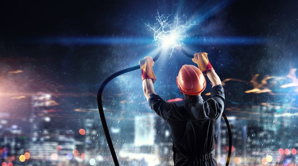 Electrician holding sparking power cables at night, city backdrop.