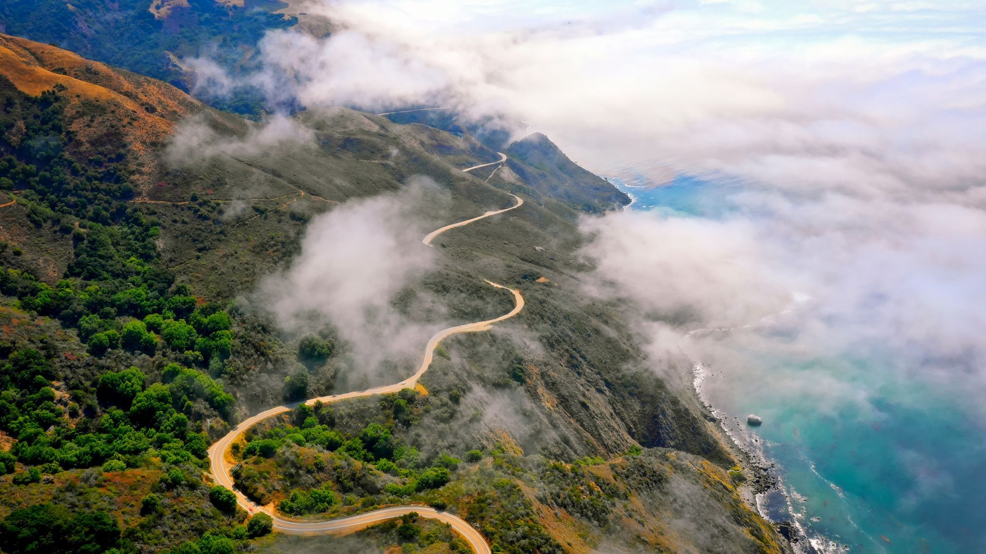 An aerial view of a winding road leading to the ocean.