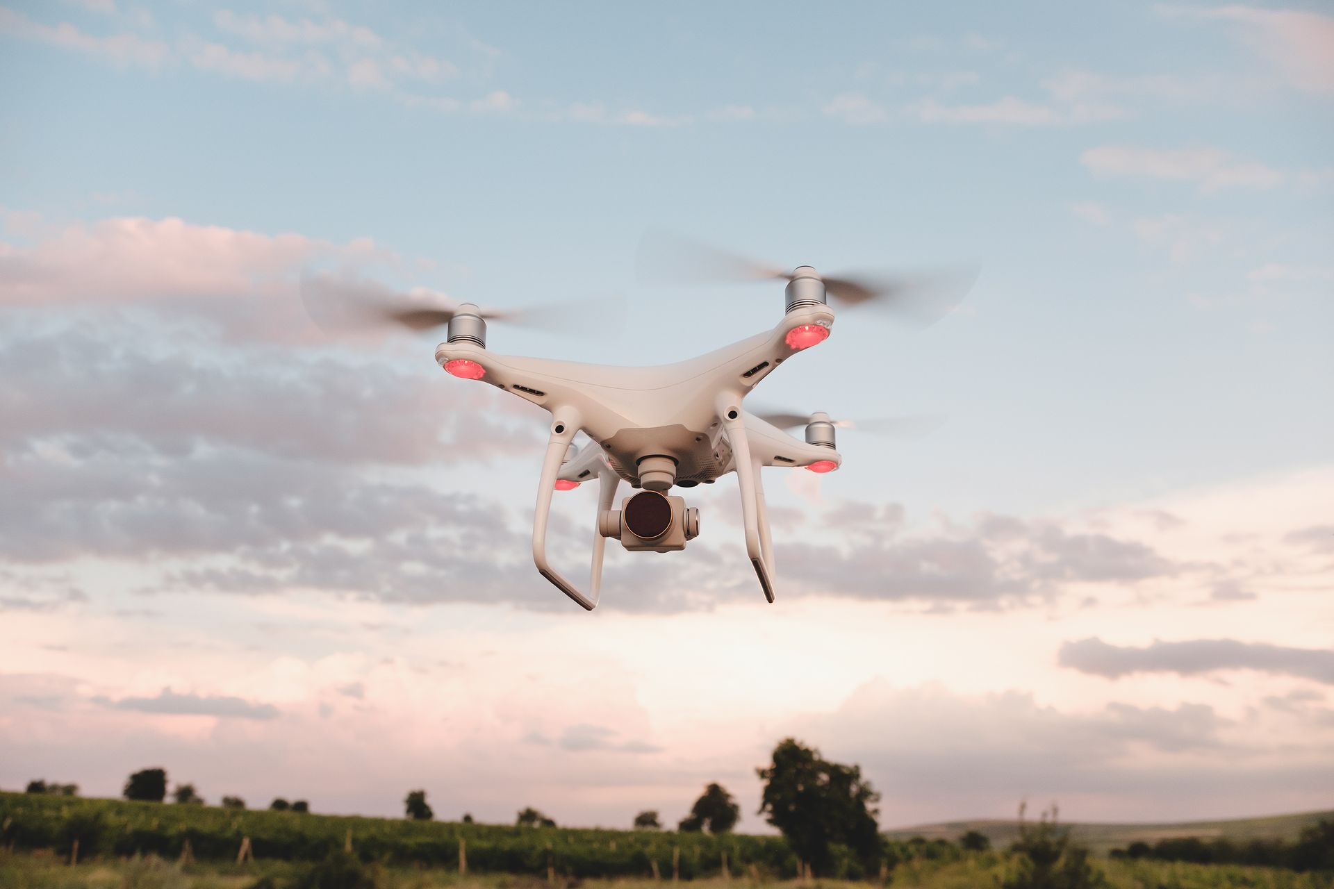 A drone is flying over a field at sunset.