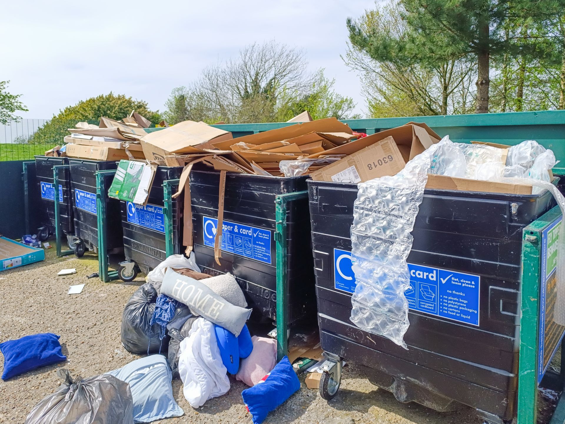 Overflowing public trash bins with bags and cardboard piled on top outdoors on a street
