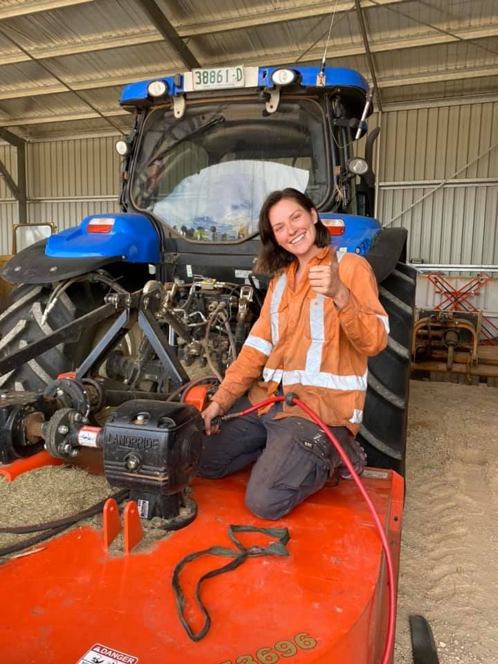 Woman in Work Clothes Kneels on a Tractor, Giving a Thumbs Up — Agile Arbor Pty Limited in Kelso, NSW