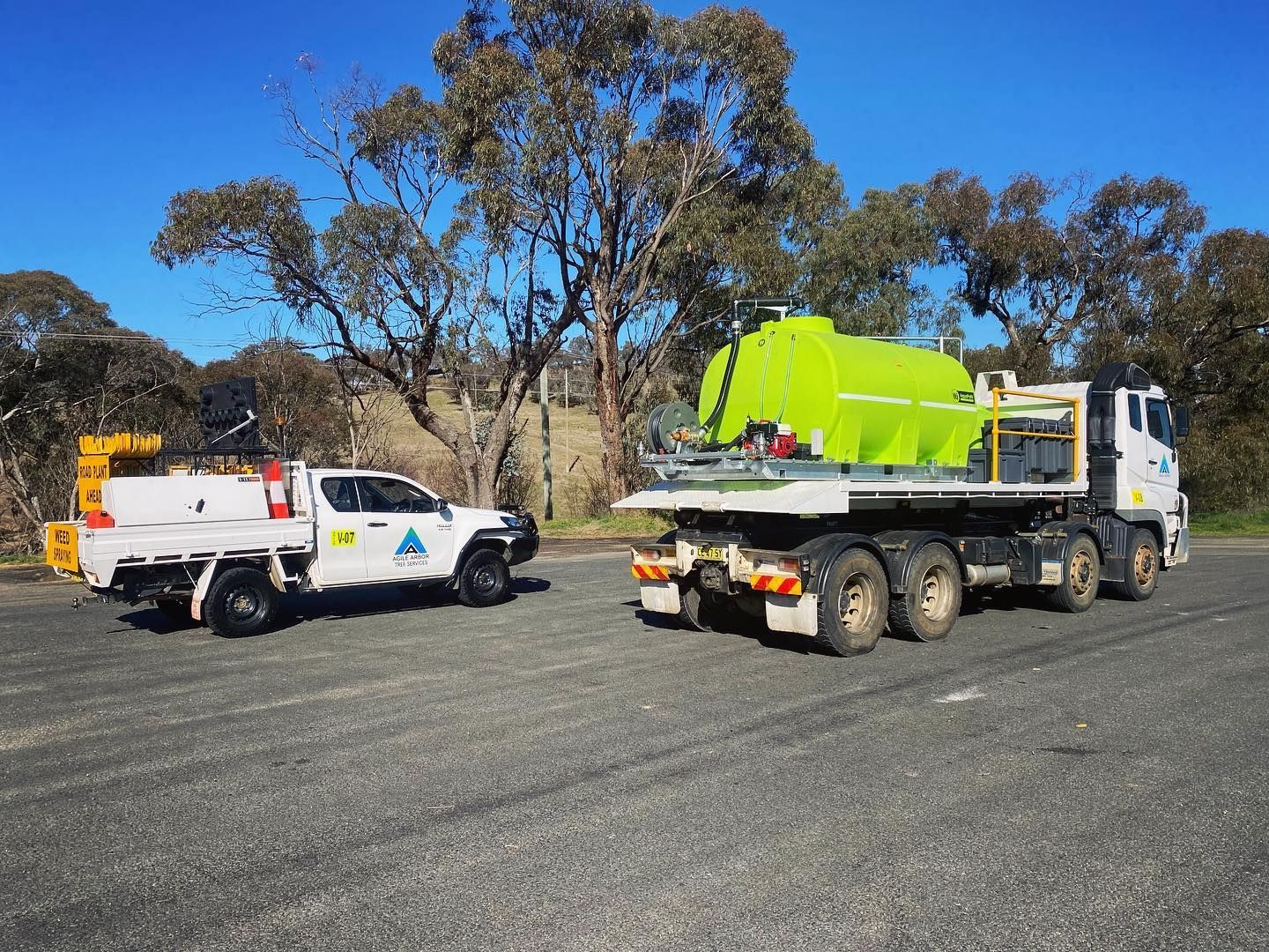 White Truck and Lime Green Water Tank Truck Parked on Gravel Road — Agile Arbor Pty Limited in Kelso, NSW