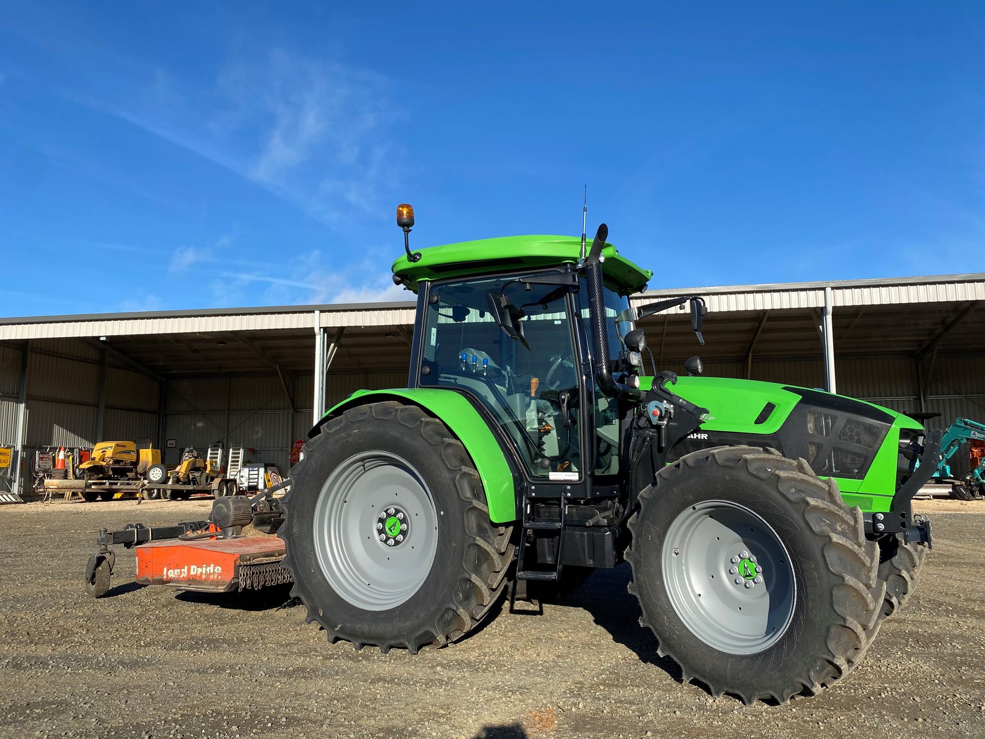 Green and black Deutz-Fahr tractor with a red implement in a gravel area  — Agile Arbor Pty Limited in Kelso, NSW