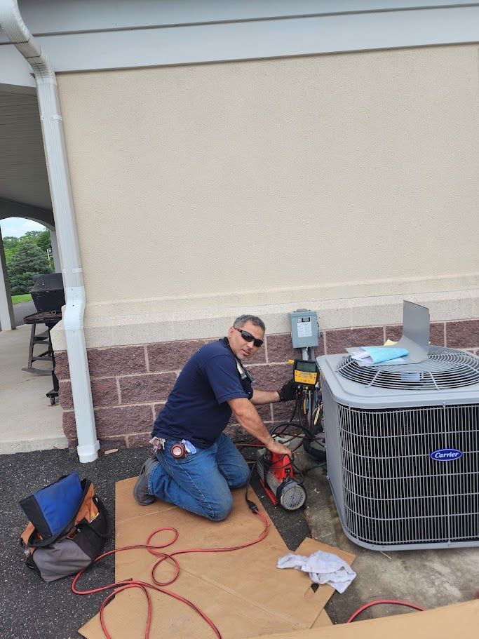 A man is working on an air conditioner outside of a building.