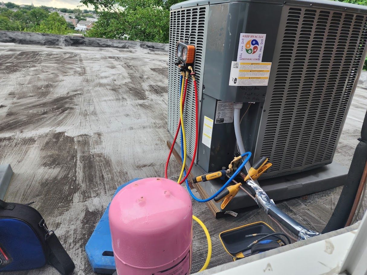 A propane tank is being filled with gas next to an air conditioner.