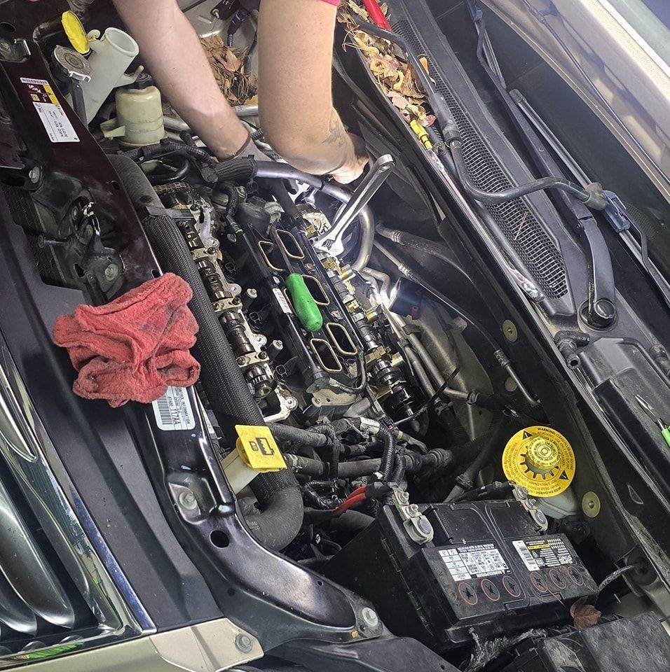 A person is working on the engine of a car with a yellow tag that says ' a ' on it