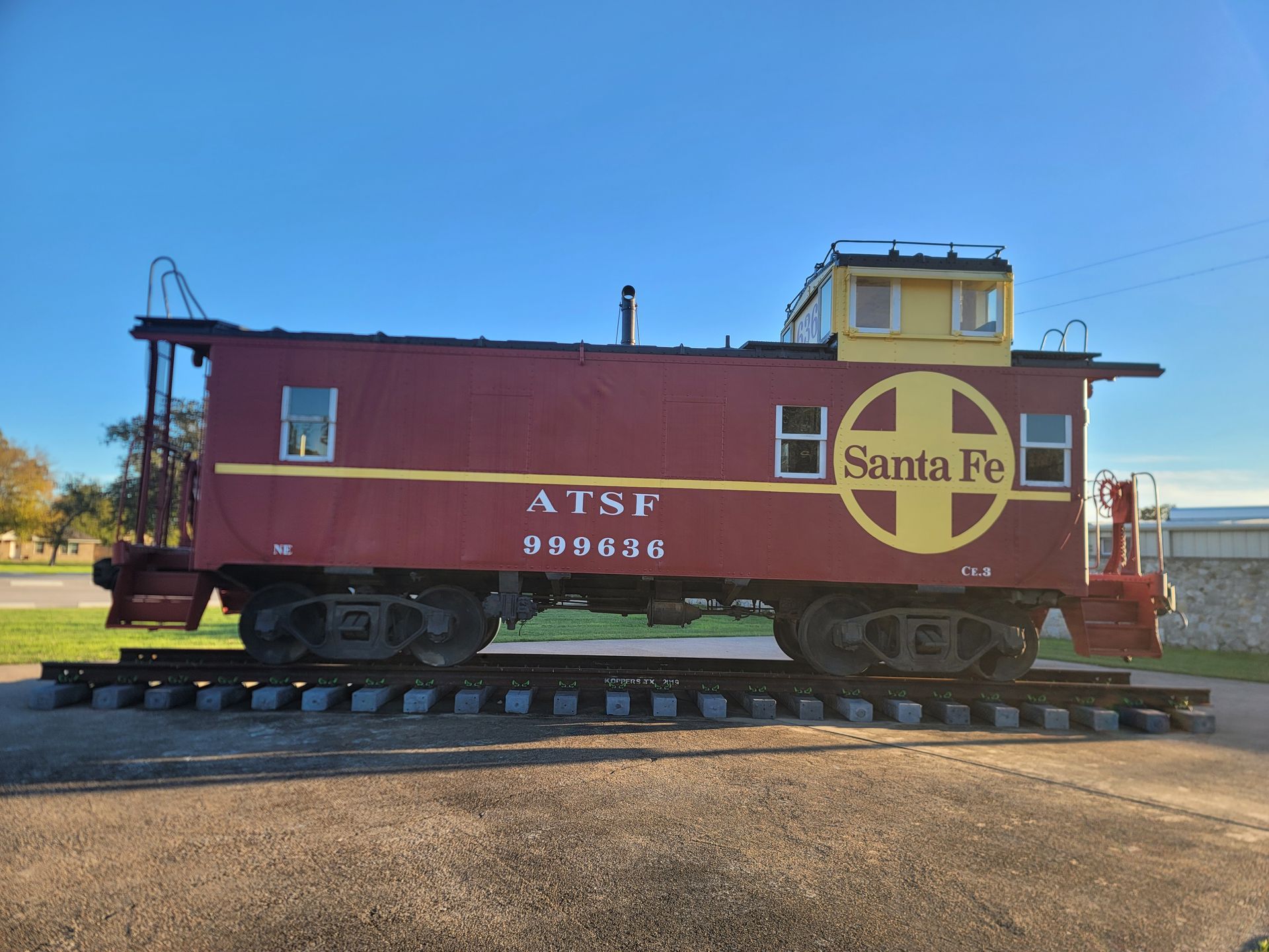 a red santa fe train car is parked on the tracks .