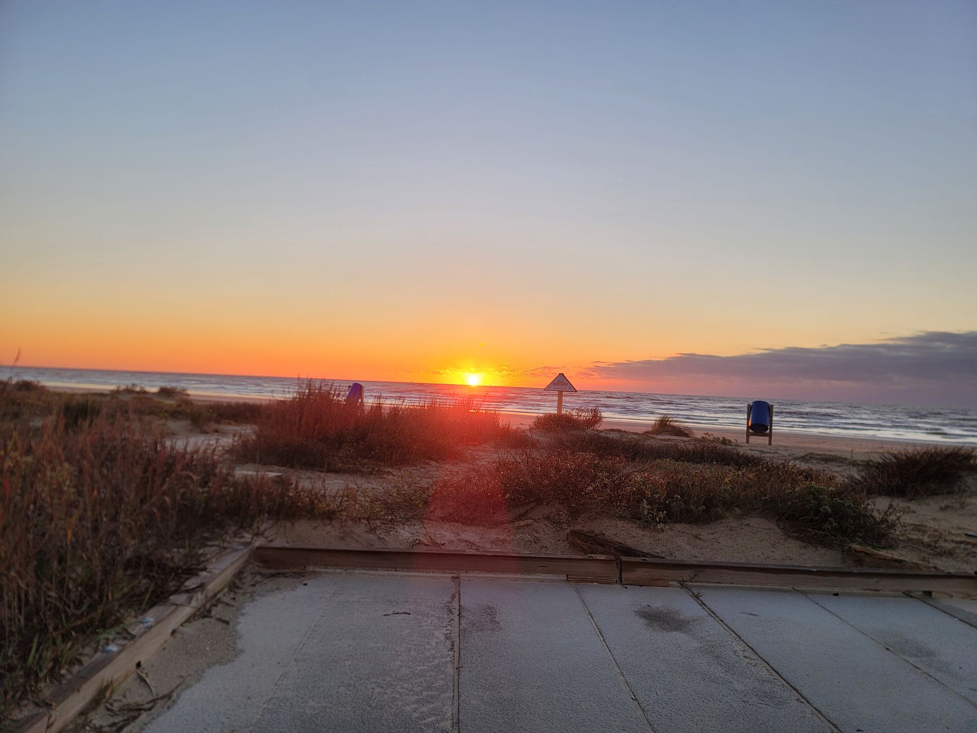 a sunset over a beach with a wooden boardwalk in the foreground .