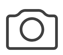 A dark gray outline icon of a digital camera on a white background.