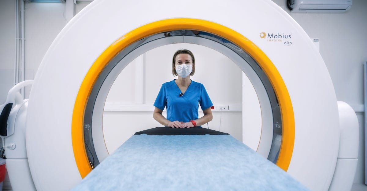 A nurse wearing a mask is standing in front of a ct scan machine.