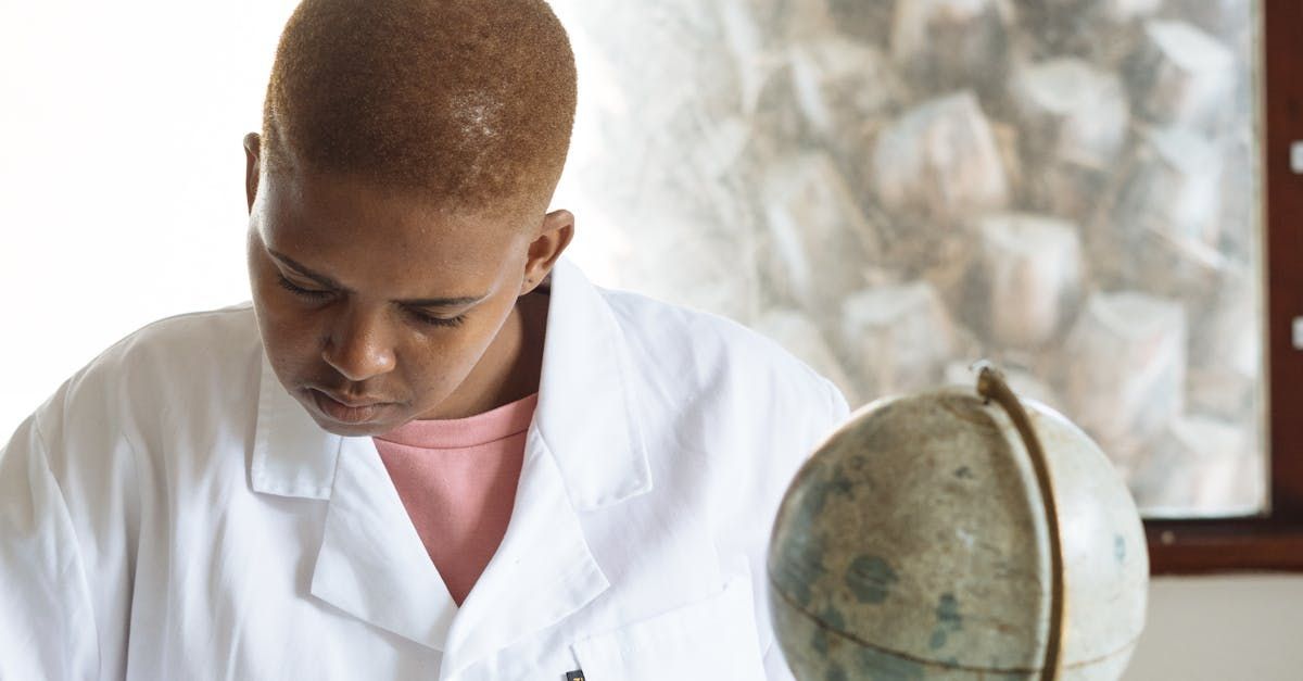 A man in a lab coat is looking at a globe.