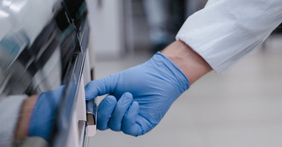 A person wearing blue gloves is opening a car door.
