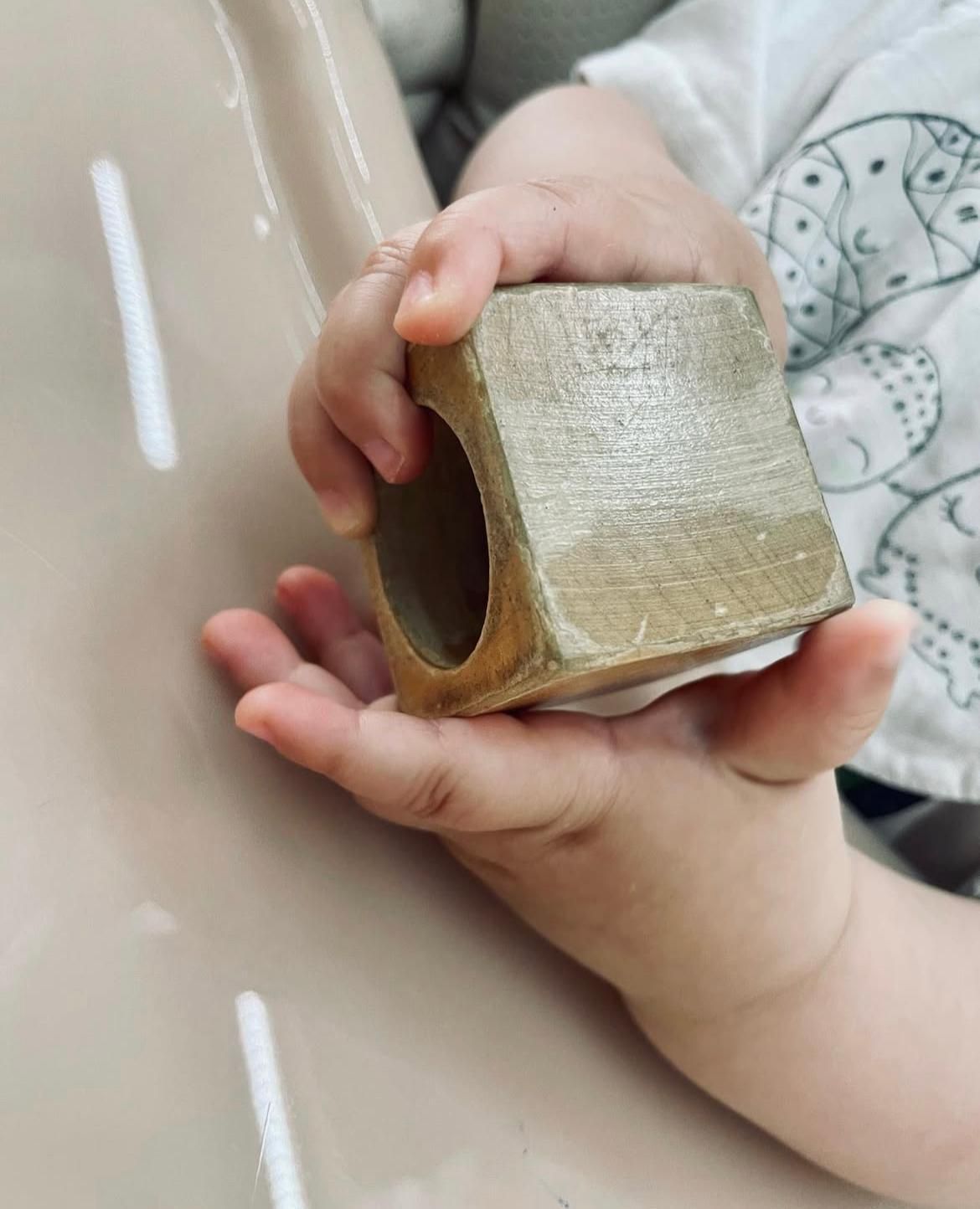 Un bambino tiene in mano un blocco di legno.