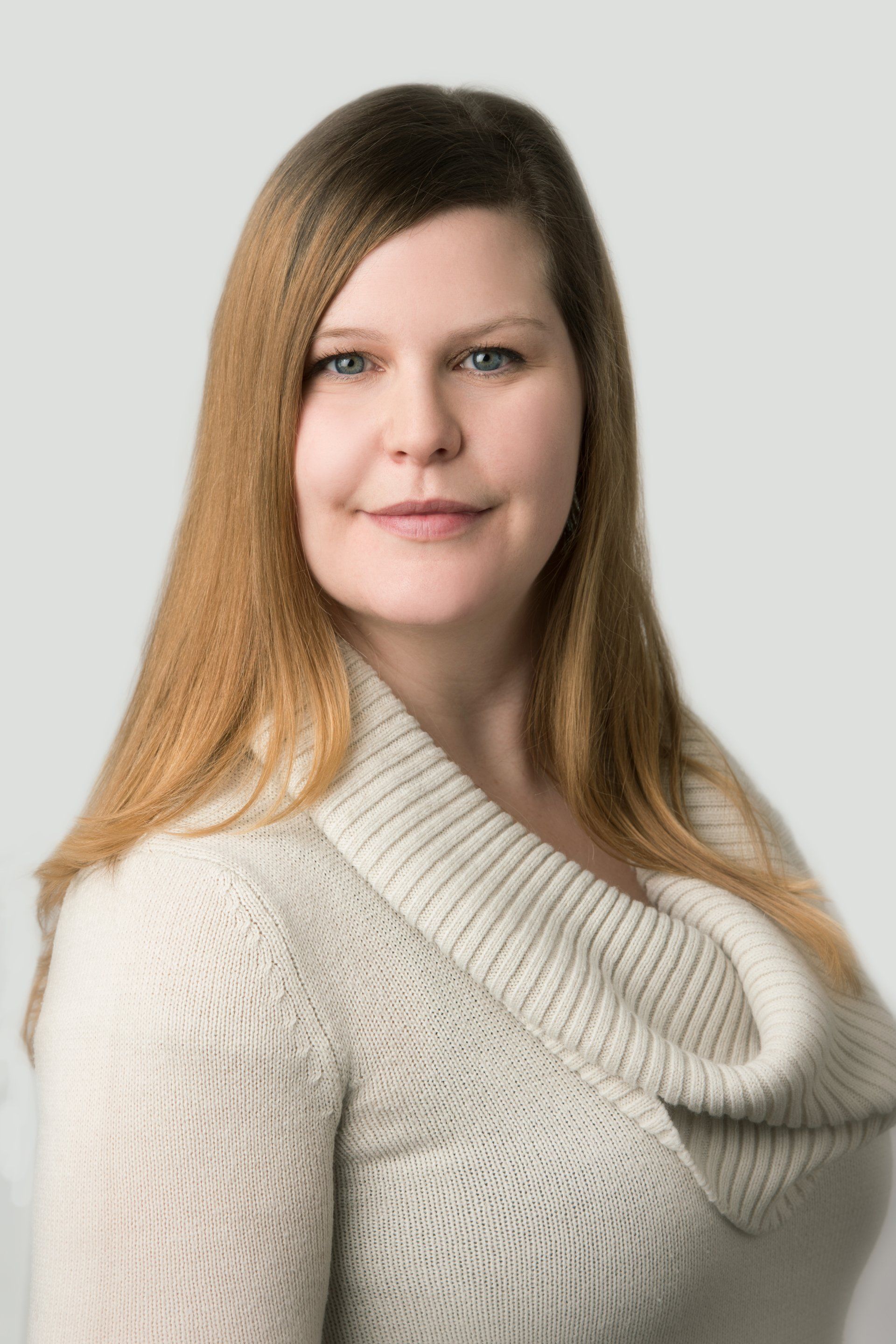 A woman in a white sweater is smiling for the camera.