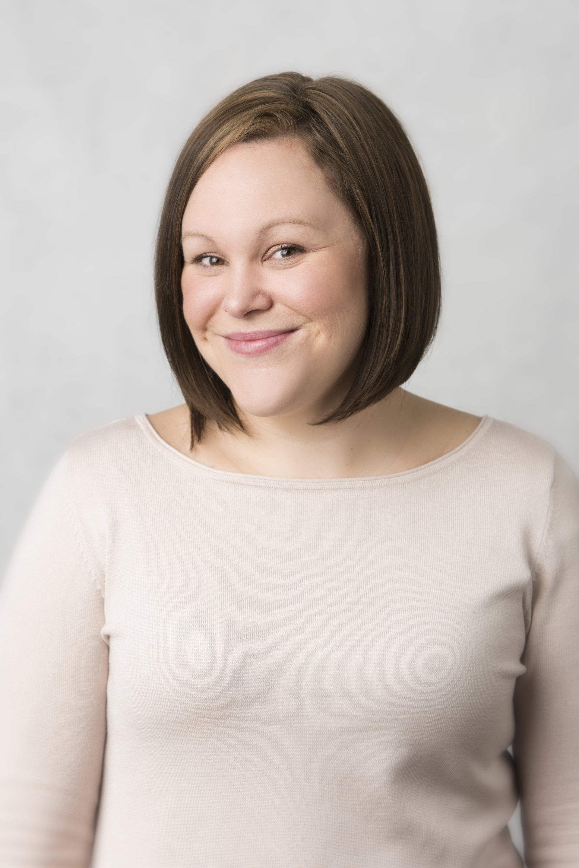 A woman in a pink sweater is smiling for the camera.