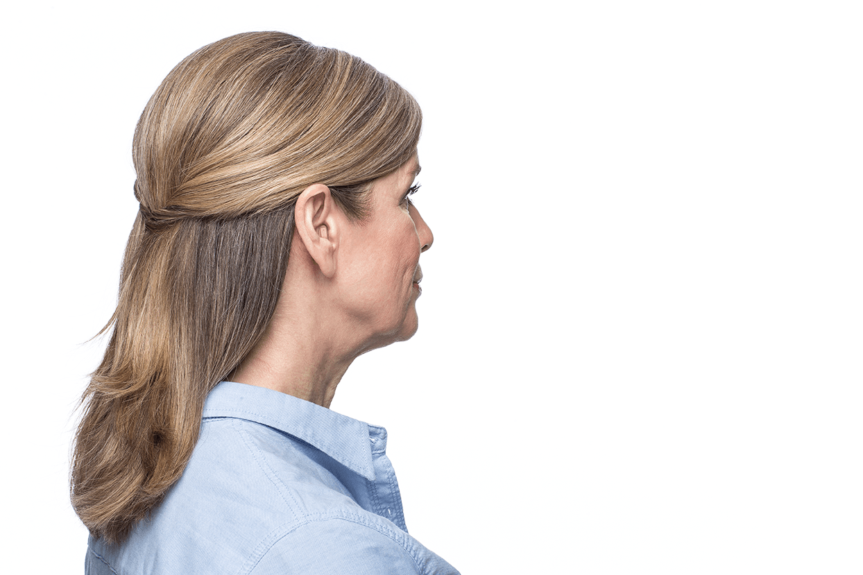 A woman wearing a hearing aid is standing in front of a white background.