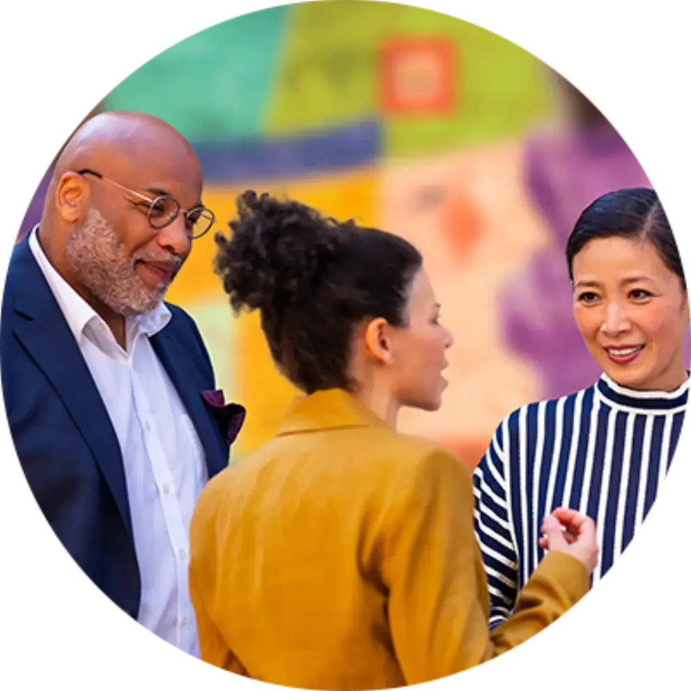 A man and two women are standing in a circle talking