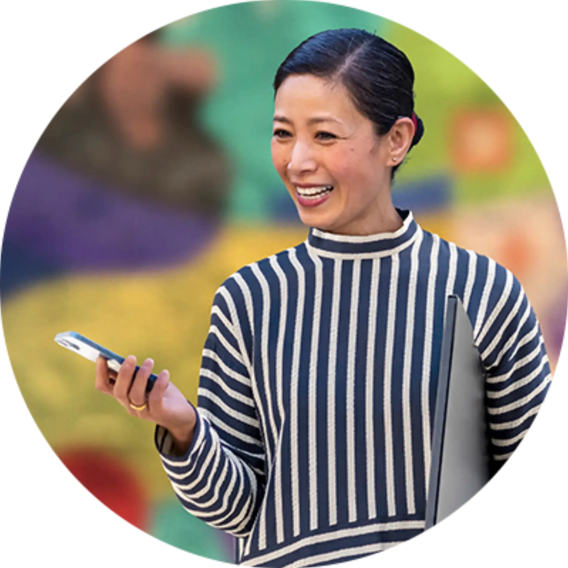 A woman in a striped sweater is smiling while holding a cell phone