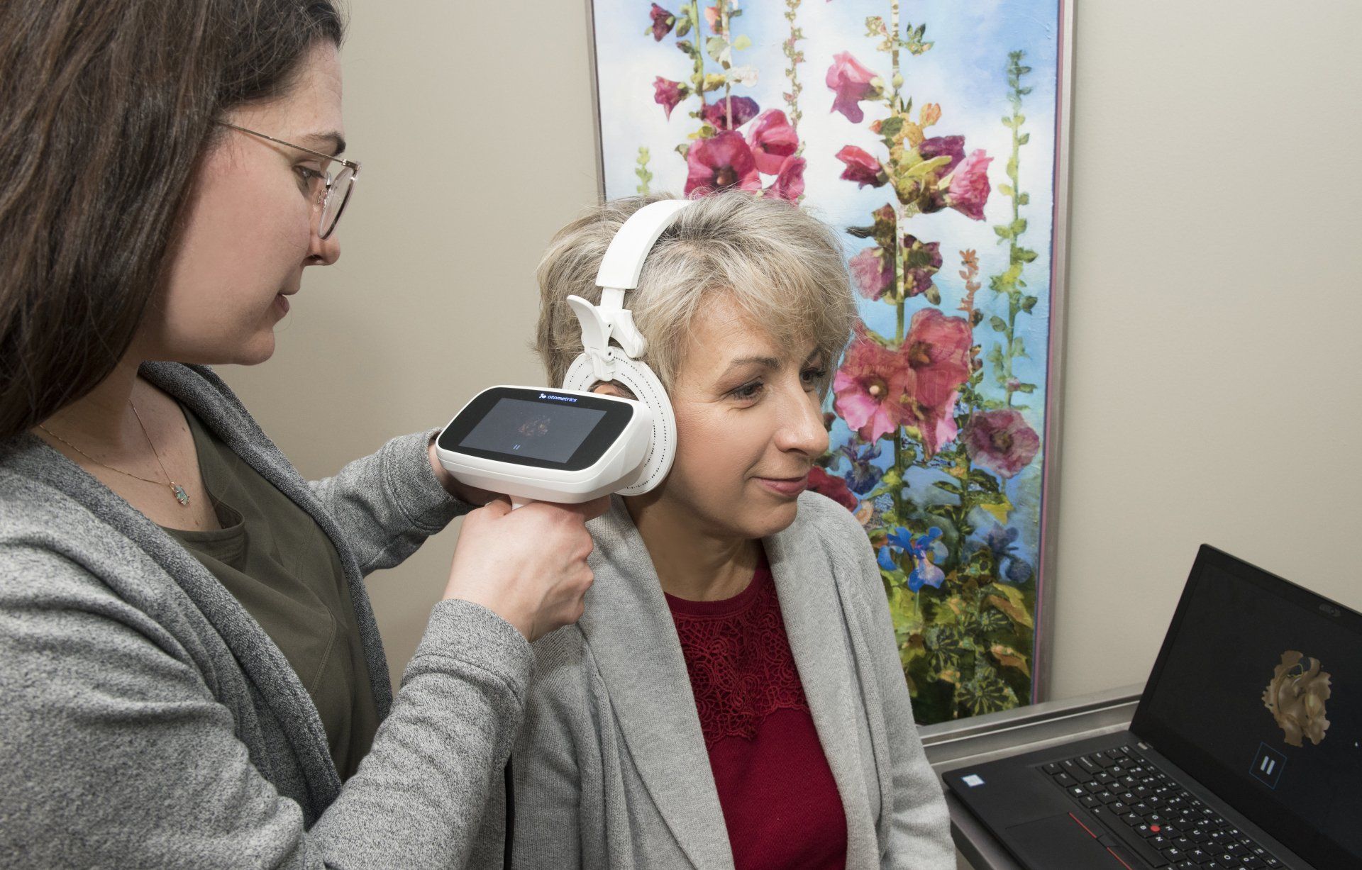 A woman is taking a picture of a woman 's ear with a camera.