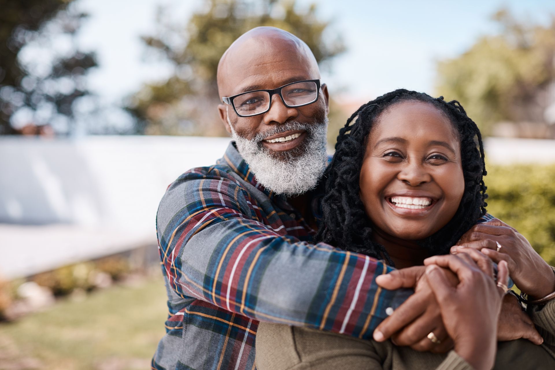 A man and a woman are hugging each other and smiling for the camera.