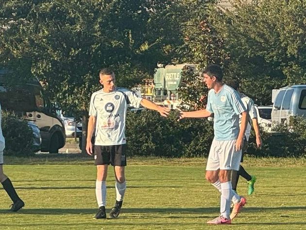 Baseball player sliding into home plate, catcher in front. Blue and gold uniforms, action shot.
