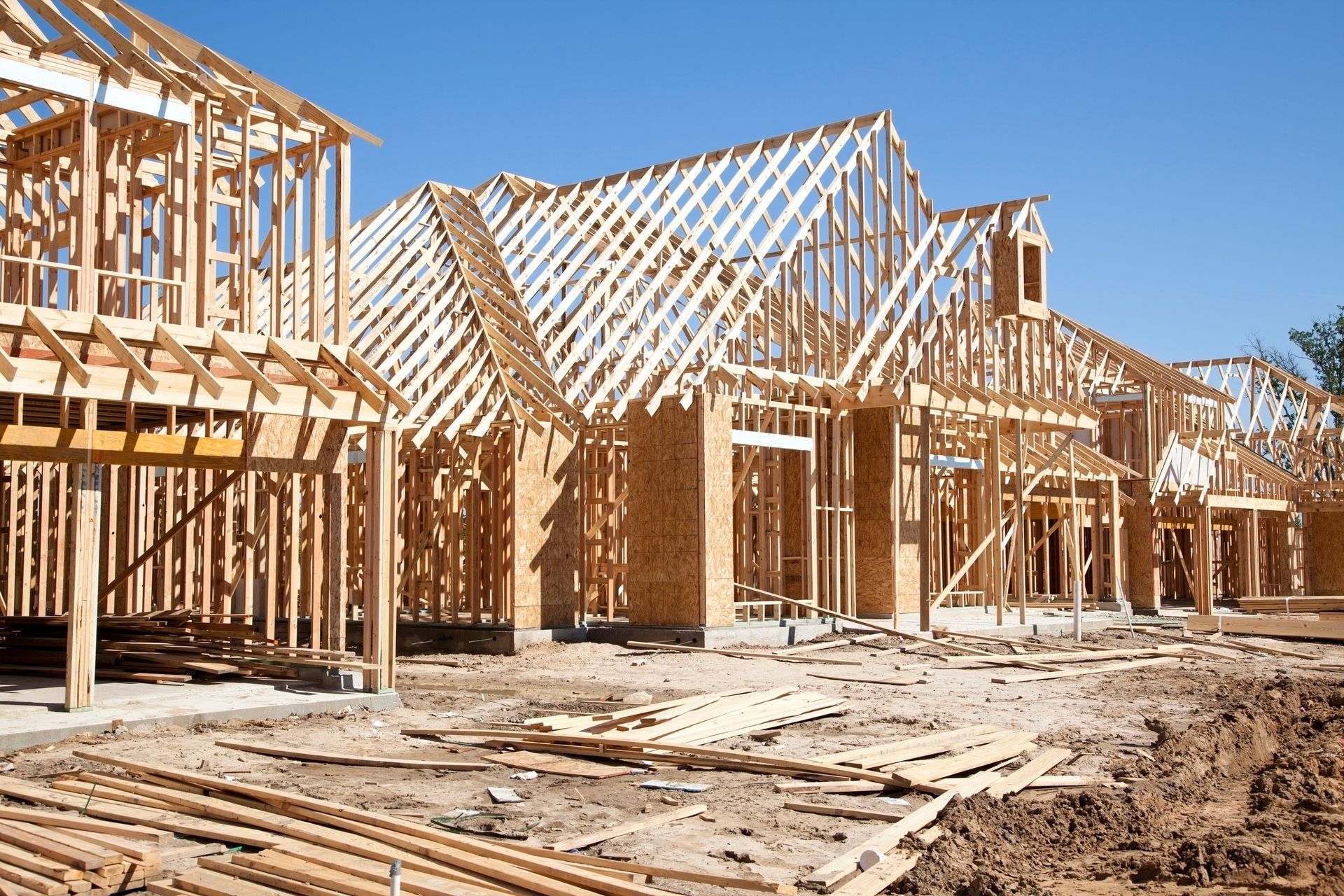 A house is being built with wooden beams and a blue sky in the background