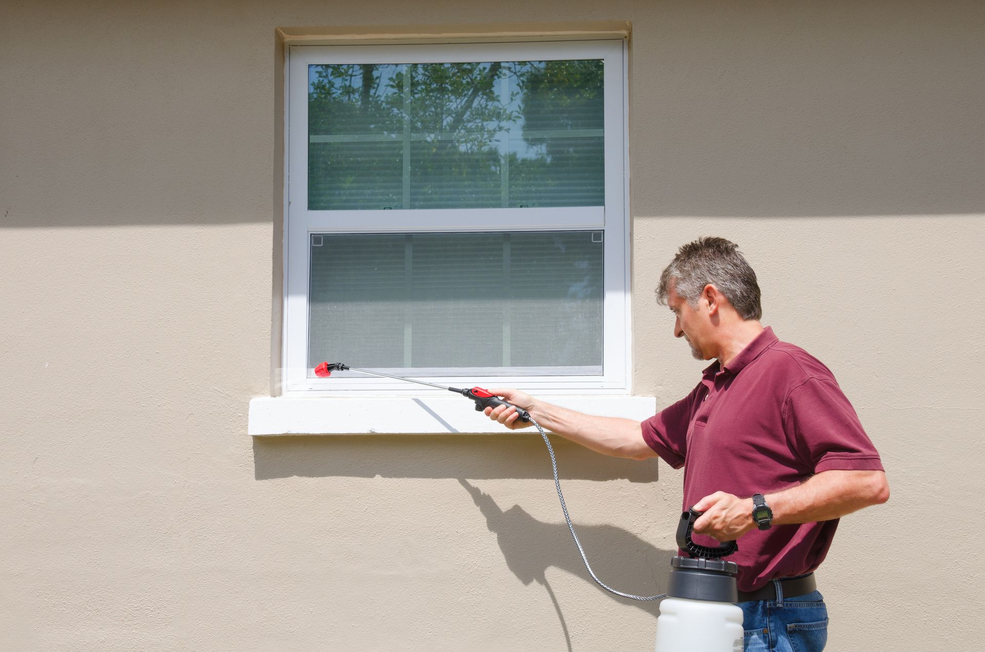 A man is spraying a window with a spray bottle.