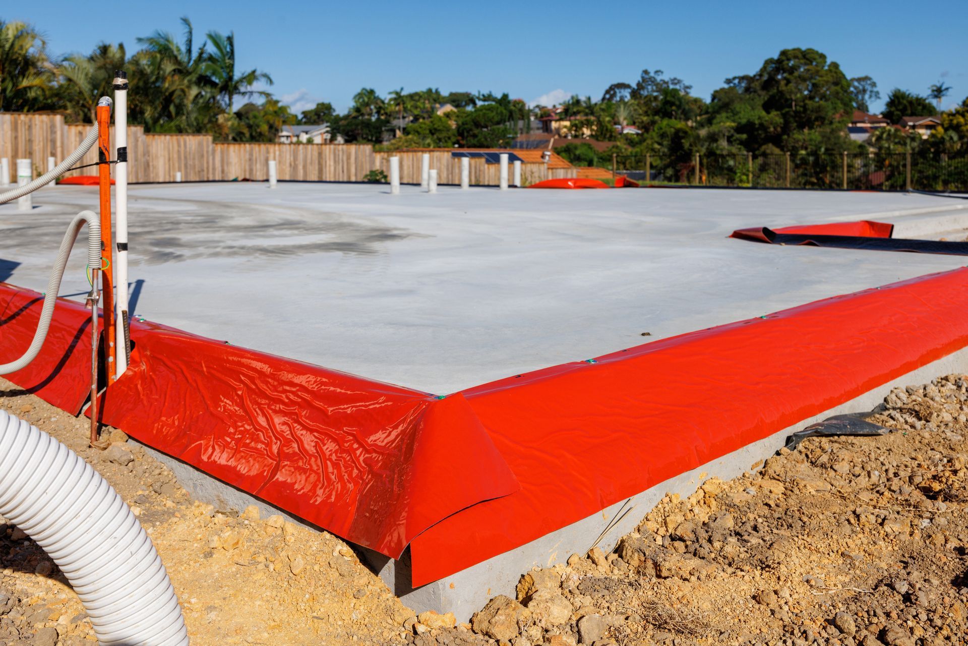 A concrete floor with a red border and a hose in the foreground