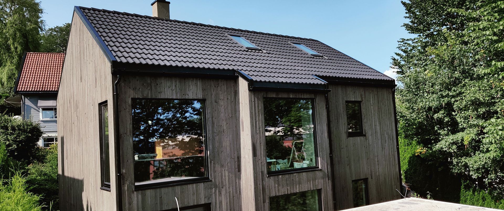 Et hus med svart tak og mange vinduer