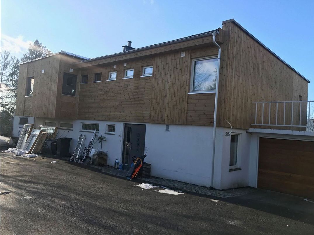 Et stort hvitt hus med trekledning blir bygget.